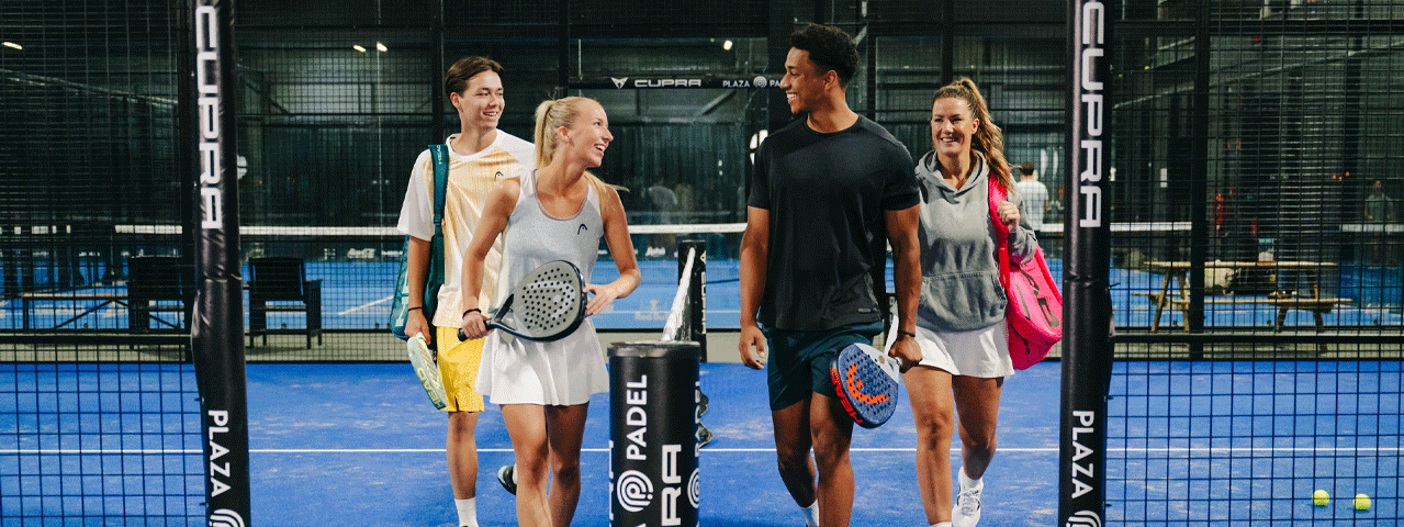 Een vriendengroep met twee vrouwen en twee mannen lopen lachend de padelbaan af. Ontvang korting op padel met de VIP-KAART.