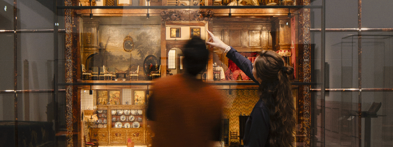 Twee bezoekers bekijken een historisch poppenhuis in het Rijksmuseum in Amsterdam, gratis te bezoeken met de VIP-KAART