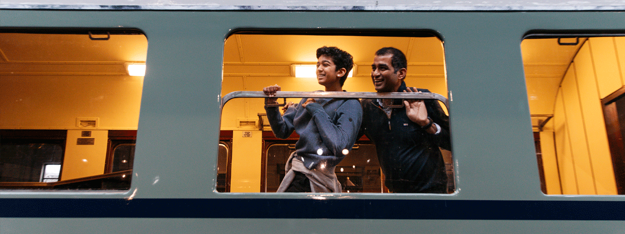 Een vader en een zoon kijken lachend uit het raam van een historische trein bij het Spoorwegmuseum. Ontvang gratis entree bij het Spoorwegmuseum met de VIP-KAART!
