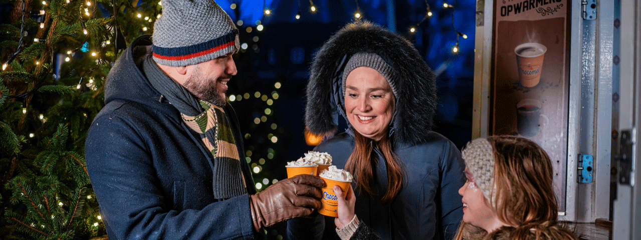 Een warm aangekleed gezin geniet van een warme chocolademelk met slagroom bij Madurodam. Met de VIP-KAART tijdelijk exclusieve actie voor de Winter Madurodam!