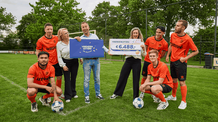 Leden van SV Voorwaarts poseren op het voetbalveld met een cheque van €6.488 van de VriendenLoterij.