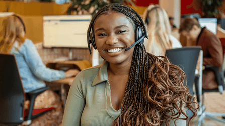 Een blije medewerker van Ledenservice met een headset op haar hoofd.