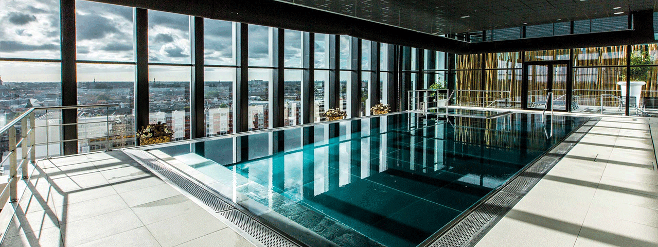 Een zwembad in een modern glazen gebouw met uitzicht op een stad bij Blue Wellness