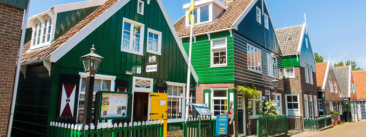 Karakteristieke groene houten huisjes in Volendam, ontvang korting op een dagje Volendam