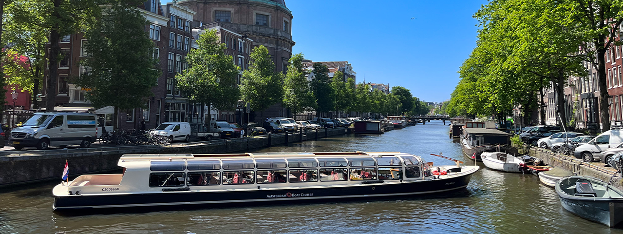 Een overdekte rondvaart boot vaart op een zonnige dag over de grachten van Amsterdam