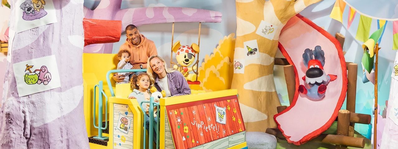 Een gezin in een kleurrijke attractie in het thema van Woezel in Pip in Avonturenpark de Tovertuin. Ontvang korting op tickets met de VIP-KAART