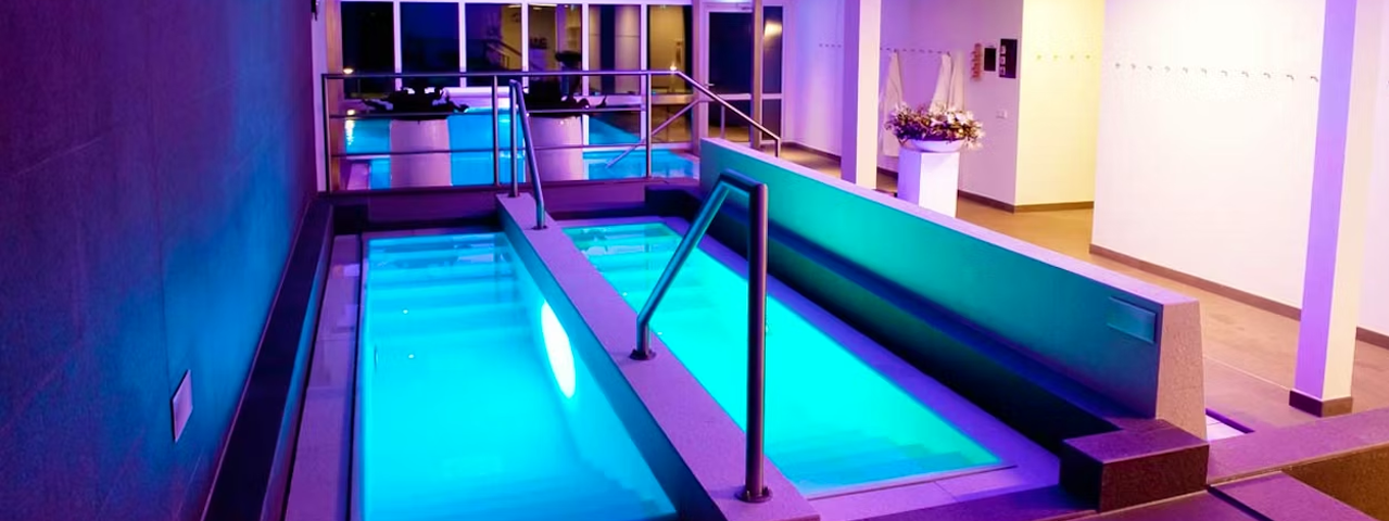 Twee smalle zwembaden in een met blauw en paars verlicht wellnessresort