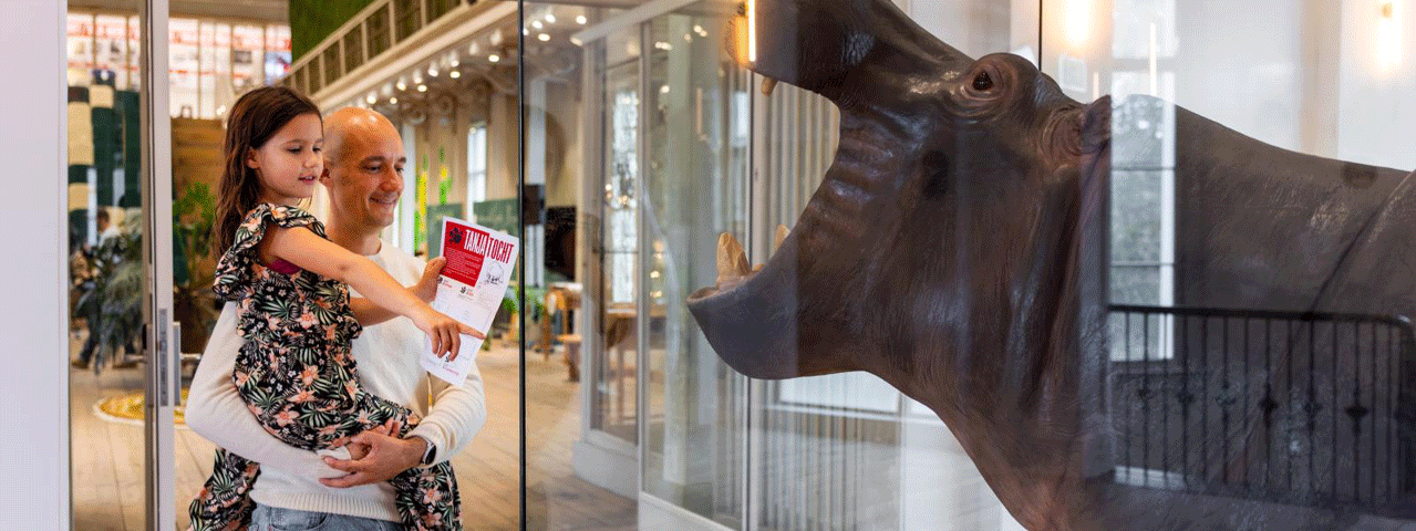 Een vader en een dochter bekijken de nijlpaal Tanja in de tentoonstelling in Groote Museum.
