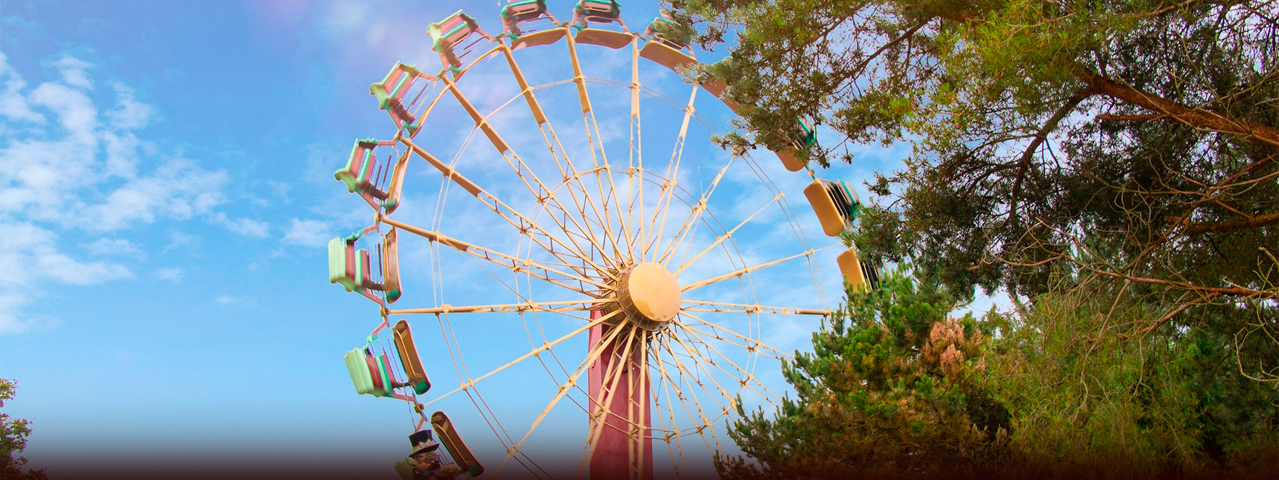 Een groot reuzenrad voor een stralende lucht in een groene omgeving bij Attractiepark Slagharen.