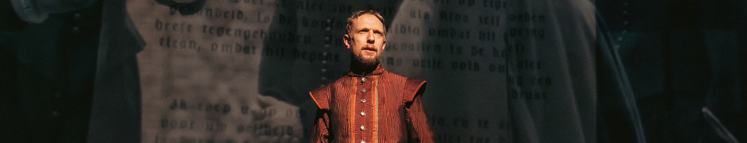 Een acteur in zestiende-eeuwse kleding en met een papier in zijn handen kijkt stoer de zaal in. Ontvang korting op Willem van Oranje de musical met de VriendenLoterij VIP-KAART.