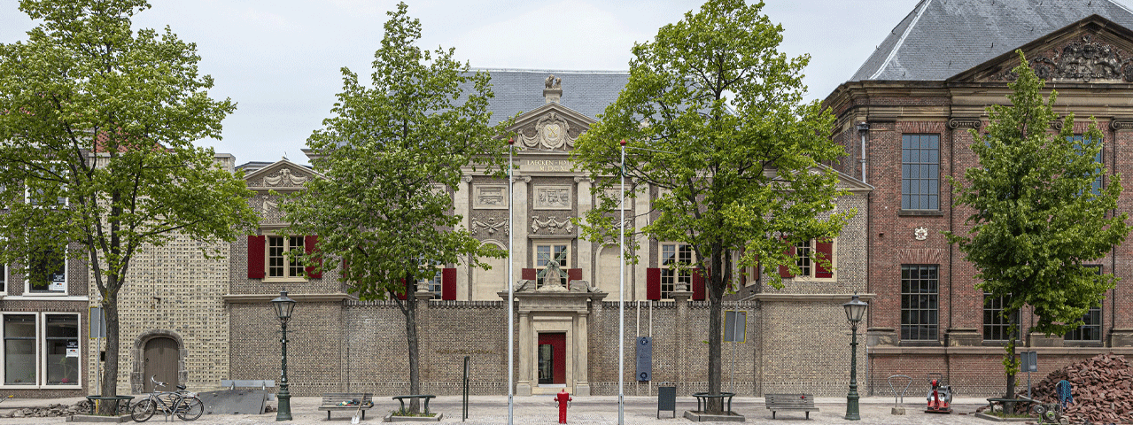 Zicht op het historische pand van Museum de Lakenhal, ommuurd met een statige poort als ingang. Het museum ligt aan een met bomen beplante gracht. Deelnemers gaan hier gratis naartoe met de VIP-KAART.