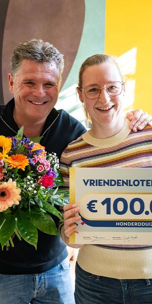 Mevrouw poseert met een cheque van €100.000 van de VriendenLoterij