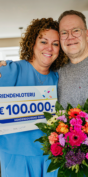 Een stel poseert met een cheque van €100.000 van de VriendenLoterij en een bos bloemen.