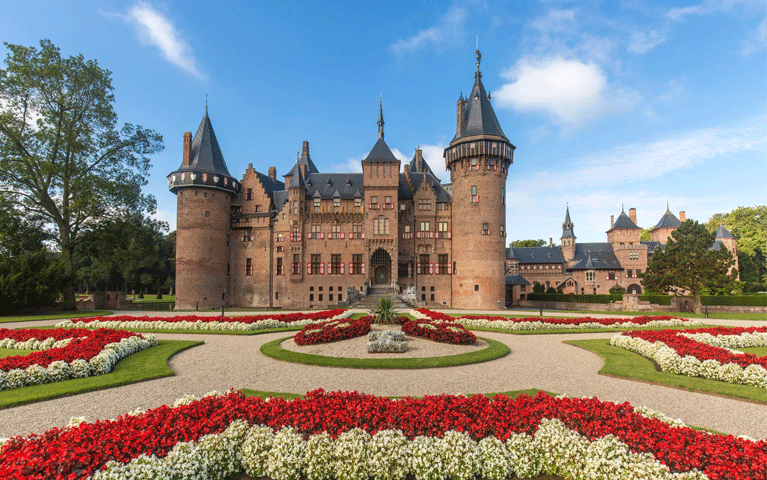 Een uitzicht op Kasteel de Haar, het grootste kasteel van Nederland, met zijn torentjes, poorten en rood-witte luiken, omringd door perfect onderhouden bloementuinen in cirkelvormige patronen. Met een VIP-KAART hebben deelnemers gratis toegang tot dit iconische historische kasteel en het omliggende park.