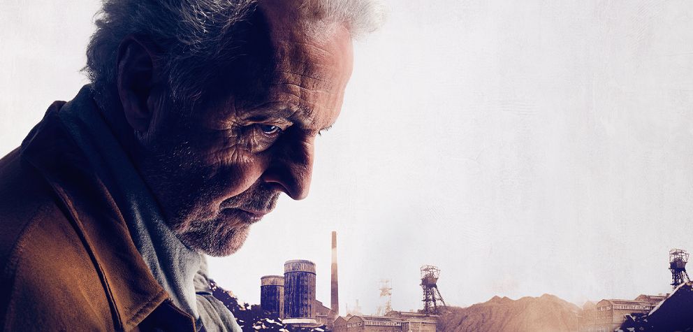 Campagnebeeld van het theaterspektakel Het Geluk van Limburg, met acteur Huub Stapel op de voorgrond en een mijnlandschap op de achtergrond. Deelnemers ontvangen korting op deze Limburgse theatervoorstelling.