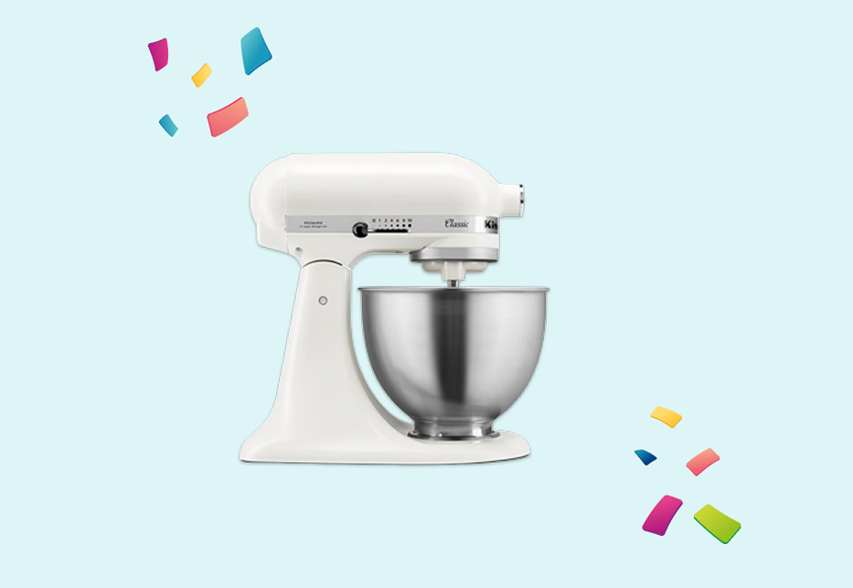 Witte staande mixer met roestvrijstalen kom op lichtblauwe achtergrond met kleurrijke confetti.