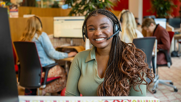 Een blije medewerker van Ledenservice met een headset op haar hoofd.