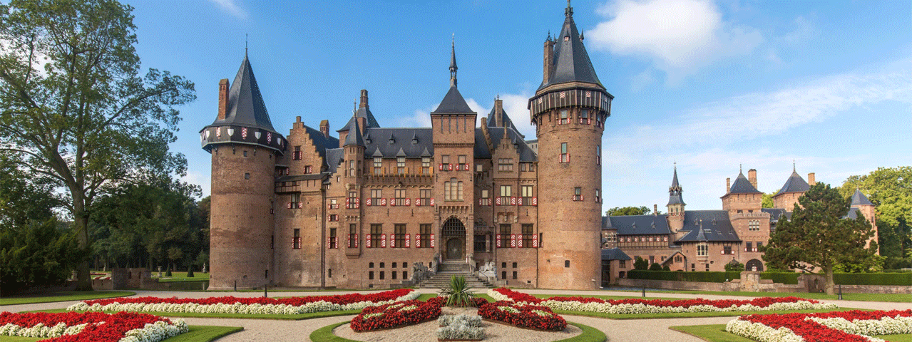 Een uitzicht op Kasteel de Haar, het grootste kasteel van Nederland, met zijn torentjes, poorten en rood-witte luiken, omringd door perfect onderhouden bloementuinen in cirkelvormige patronen. Met een VIP-KAART hebben deelnemers gratis toegang tot dit iconische historische kasteel en het omliggende park.