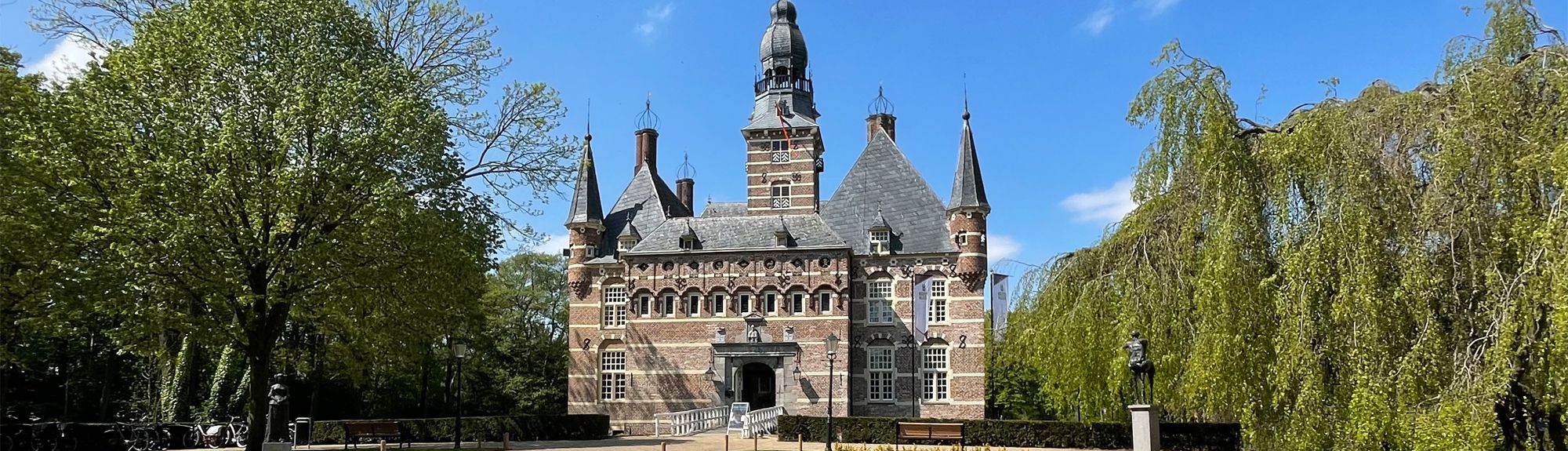 Het sprookjesachtige Kasteel Wijchen in een groene omgeving vol bomen. Het kasteel heeft veel details en torens. Dit mooie kasteel bezoekt u met korting met de VIP-KAART.