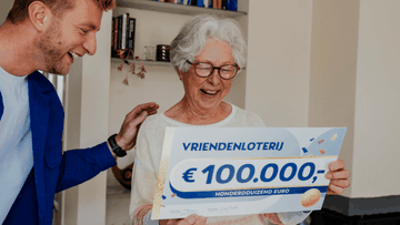 Een oudere vrouw kijkt verrast en blij naar een cheque van €100.000 van de VriendenLoterij terwijl iemand naast haar meekijkt.