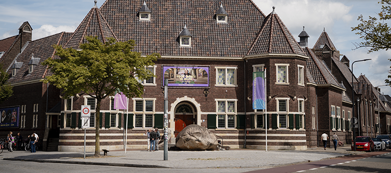 Rijksmuseum Twenthe in Enschede, historisch gebouw met bakstenen gevel en banners voor kunsttentoonstelling.